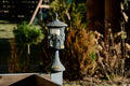 Outdoor lantern standing in a garden bed among greenery