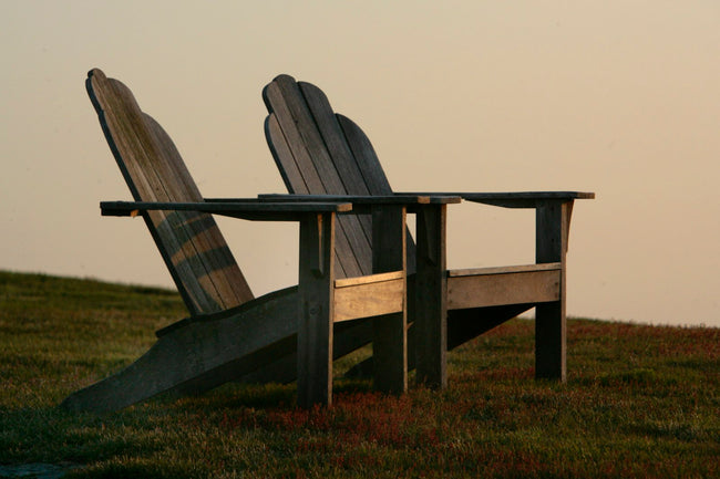 A pair of Adirondack chairs on a green lawn