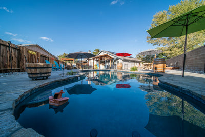 Outdoor patio umbrella open beside a pool in bright daylight