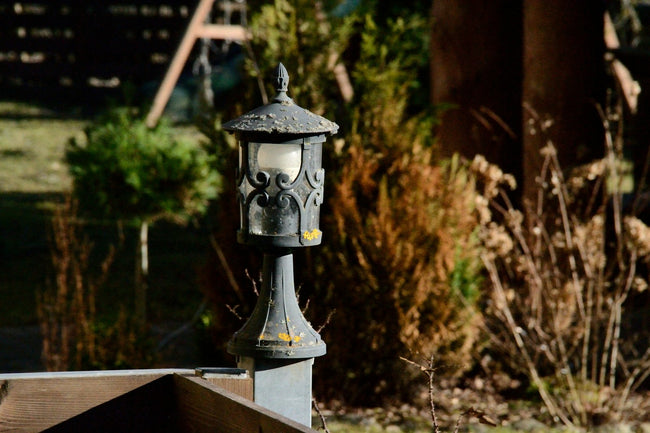 Outdoor lantern standing in a garden bed among greenery
